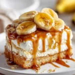 Bananas Foster Poke Cake with Caramel Sauce topped with fresh banana slices and dripping caramel on a white plate.