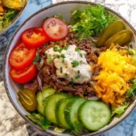 Burger Bowls Caramelized Onion Aioli served with fresh vegetables, ground beef, and shredded cheese in a bowl.