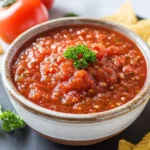 A rustic bowl filled with vibrant Fire Roasted Salsa, garnished with fresh parsley and served with tortilla chips.