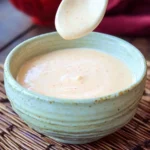 Creamy Japanese Steakhouse White Sauce in a green ceramic bowl with a white spoon lifting some sauce.