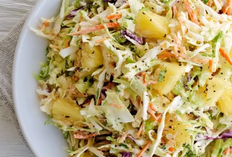 Fresh Pineapple Coleslaw with shredded cabbage, carrots, and pineapple chunks in a creamy dressing served in a white bowl.