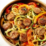 Sausage and Peppers with Zucchini Noodles served in a bowl with fresh herbs on top.