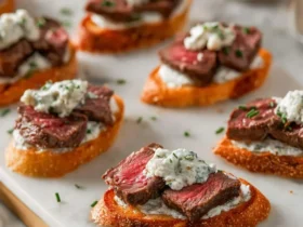 Elegant Steak Crostini with Boursin Cheese on toasted baguette slices, topped with fresh herbs.