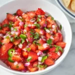 Fresh Strawberry Jalapeño Salsa in a white bowl with diced strawberries, red onion, cilantro, and jalapeño slices.