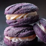 Stack of purple Ube crinkle sandwich cookies filled with creamy white frosting and dusted with powdered sugar.
