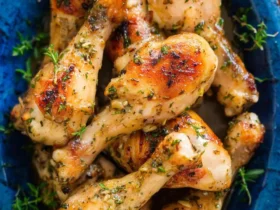 Golden brown Baked Chicken Legs with Garlic and Dijon arranged in a blue serving dish, garnished with fresh herbs.