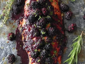 Baked Salmon with Blackberry Barbecue Sauce 53 Baked Salmon with Blackberry Barbecue Sauce topped with fresh blackberries and herbs on a rustic metal surface.