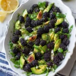 Fresh Blackberry Avocado Arugula Salad with figs and herbs in a white oval bowl, lemon on the side.