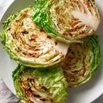 Four golden-brown grilled Cabbage Steaks arranged on a white plate with charred edges and tender centers.
