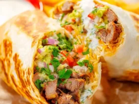 California Burrito Recipe 53 California Burrito Recipe showing a grilled burrito cut in half with carne asada, fries, guacamole, and sour cream.