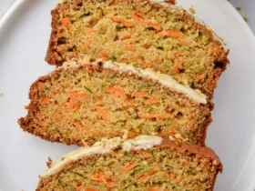 Carrot Zucchini Bread 39 Three slices of moist Carrot Zucchini Bread with cream cheese frosting arranged on a white plate.