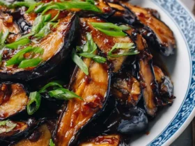 Chinese Eggplant with Garlic Sauce served on a blue and white plate, garnished with fresh green onions.