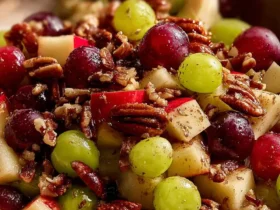 Cinnamon Apple Grape Salad 35 A bowl of Cinnamon Apple Grape Salad with red and green grapes, diced apples, and pecans sprinkled on top.