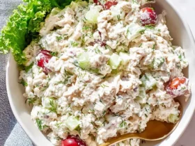 A bowl of creamy cottage cheese chicken salad with grapes, celery, dill, and lettuce garnish with a gold spoon.