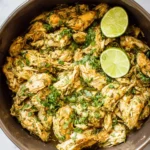 Shredded Crockpot Cilantro Lime Chicken topped with fresh cilantro and lime slices in a metal bowl.