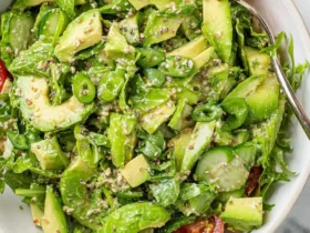 Green Goddess Avocado Salad 53 Fresh Green Goddess Avocado Salad with cucumber, spinach, and sesame seeds in a white bowl with a serving spoon.