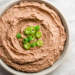 Creamy Instant Pot Refried Beans in a white bowl topped with fresh sliced jalapenos.
