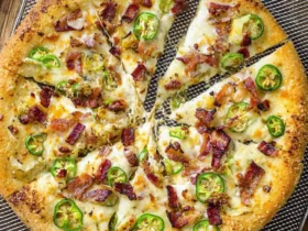 A sliced Jalapeno Popper Pizza topped with melted cheese, crispy bacon, and fresh jalapeño slices on a golden crust.