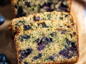 Sliced low carb Blueberry Banana Zucchini Bread with visible blueberries and green zucchini flecks on parchment paper.