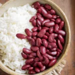 A rustic bowl filled with fluffy white rice and cooked red kidney beans, showcasing a classic Red Beans and Rice dish.