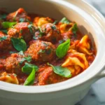Slow Cooker Tortellini Meatballs in a creamy tomato sauce topped with fresh basil leaves.