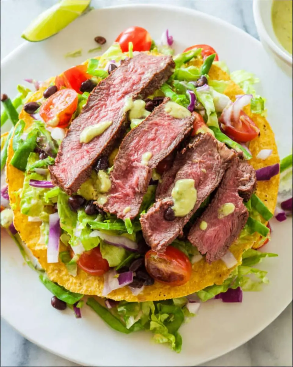 Steak tostada salad ingredients arranged on a cutting board with marinated steak and fresh vegetables