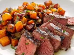 Steak with Sweet Potato Hash 45 Sliced medium-rare steak with sweet potato hash served on a white plate, garnished with fresh herbs.