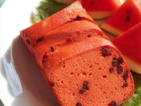 Sliced Watermelon Bread with chocolate chips arranged on a white plate with fresh watermelon wedges and mint leaves.