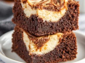 Two stacked Mocha Cheesecake Brownies with swirled cream cheese topping on a white plate.