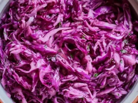 purple cabbage recipe salad 47 A bowl of vibrant purple cabbage recipe salad with fresh herbs and light dressing on a wooden surface.