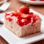 A slice of strawberry sheet cake topped with fresh strawberries and glossy strawberry glaze on a white plate.