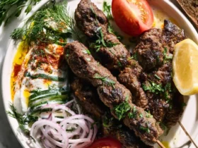 Turkish Beef Kofta Recipe 37 Grilled Turkish Beef Kofta Recipe served on a plate with yogurt sauce, fresh vegetables, and herbs.
